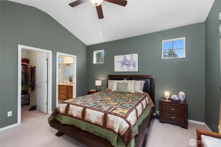 Primary bedroom with vaulted ceiling, walk-in closet, and primary bathroom with newly updated shower.