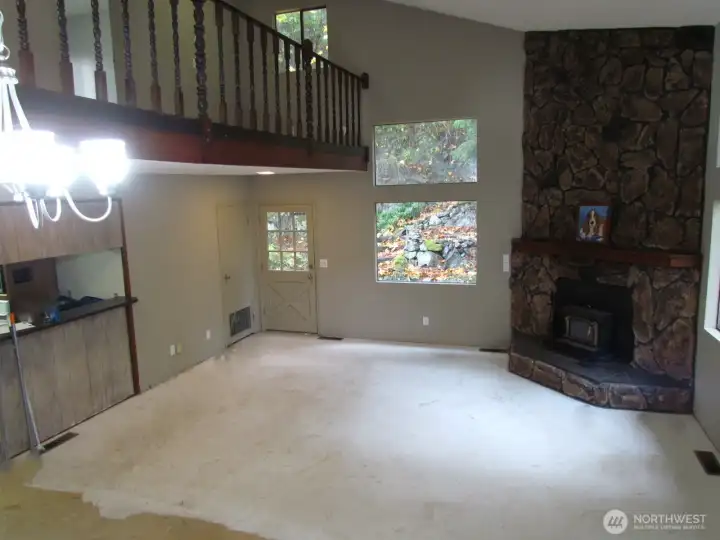 Living Room with a nice wood burning fireplace insert. The dining area is located at the bottom of the stairs under the shiny light. There is a good size coat closet and another door that leads out onto the deck.