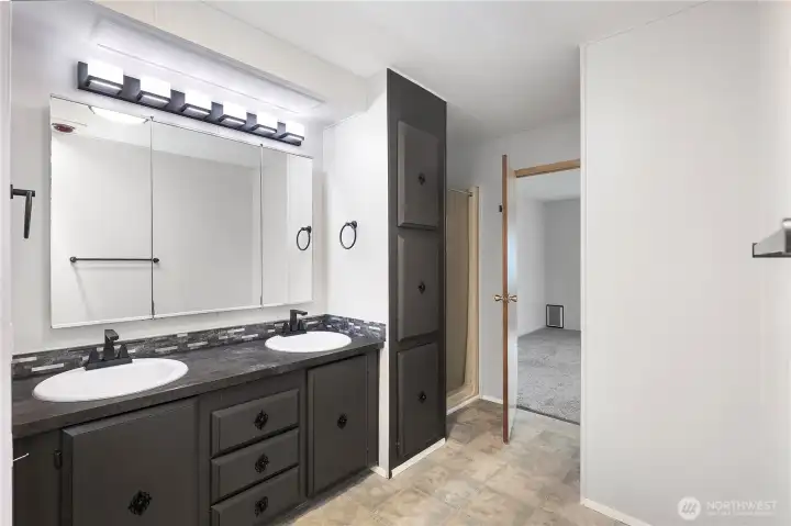 View from your beautiful primary en-suite bathroom towards primary bedroom. Notice the double vanity with upgraded lighting and fixtures. Brand new walk in shower lies directly to the right.