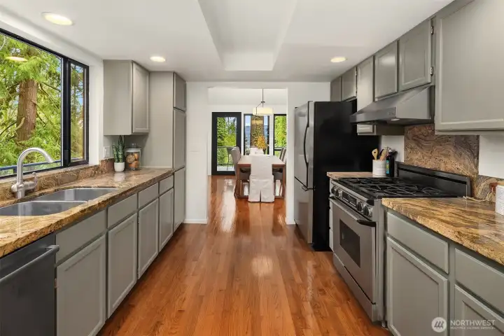 Updated kitchen featuring refreshed cabinetry, granite countertops, stainless steel appliances, and hardwood floors