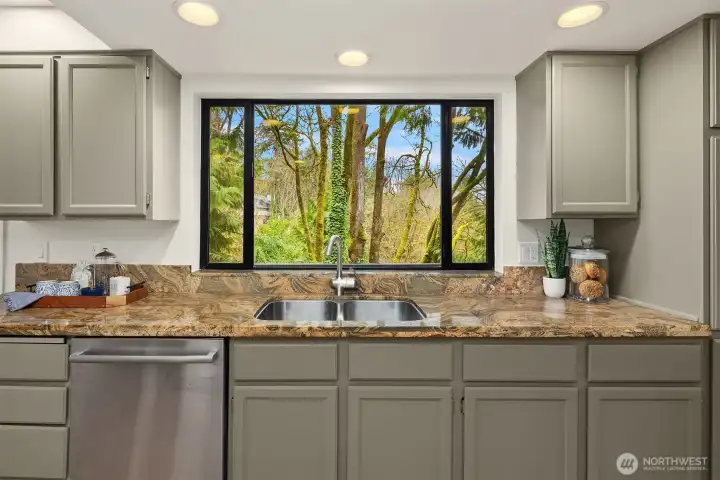 Kitchen sink perfectly positioned beneath a large window capturing peaceful evergreen views