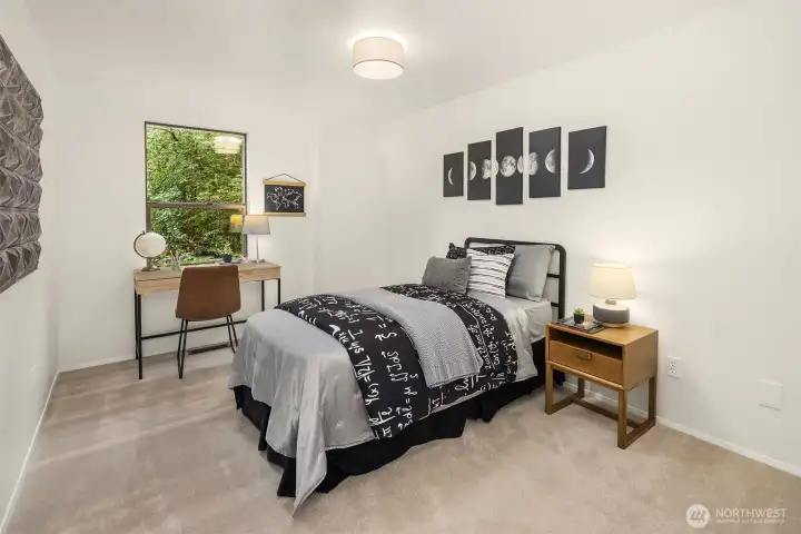 Comfortable lower-level bedroom with natural light and peaceful greenbelt outlook