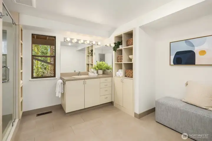 Generous lower-level bathroom with expansive vanity, glass shower, and custom built-in storage