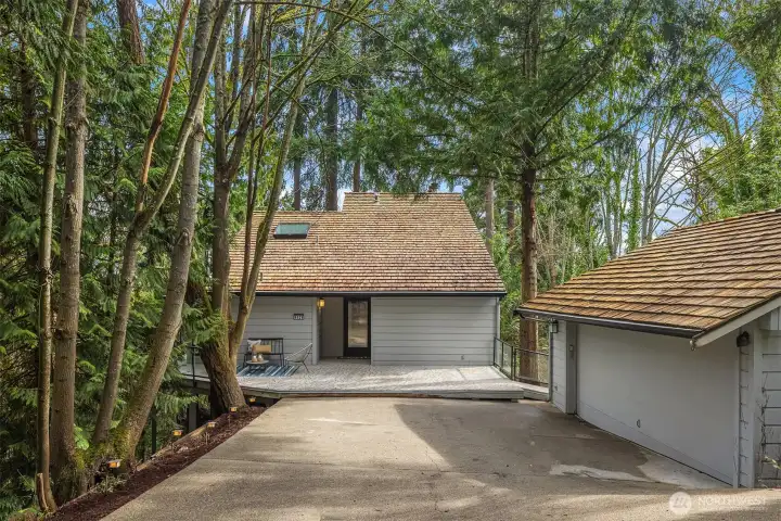 Private drive approach with detached garage and inviting entry surrounded by mature Pacific Northwest evergreens.