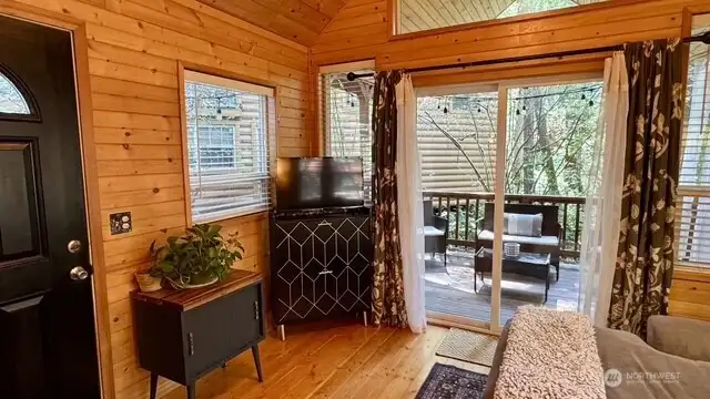 LIVING ROOM OPENS ON TO SIDE COVERED PORCH WITH SLIDING GLASS DOORS.