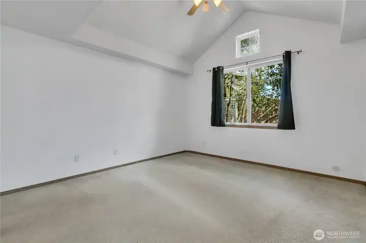 Primary bedroom with high ceilings, natural light and ceiling fan.
