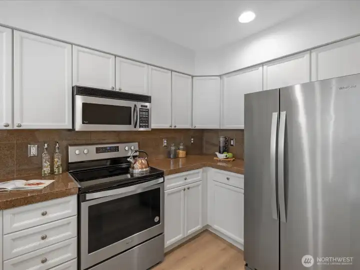 Kitchen with freshly cabinetry, countertop workspace, and stainless steel appliances including range, microwave, and refrigerator. Kitchen with freshly cabinetry, countertop workspace, and stainless steel appliances including range, microwave, and refrigerator.