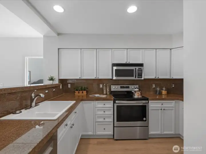 Kitchen with refreshed cabinetry, countertop workspace, and appliances including range, microwave, and dishwasher. Open connection to dining and living areas. Kitchen with refreshed cabinetry, countertop workspace, and appliances including range, microwave, and dishwasher. Open connection to dining and living areas.
