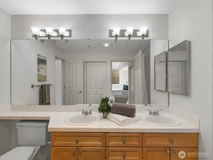 Ensuite bathroom with double vanity, dual sinks, and full-width mirror, providing functional layout with storage and lighting. Ensuite bathroom with double vanity, dual sinks, and full-width mirror, providing functional layout with storage and lighting.
