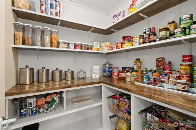 Discover the amazing pantry, featuring wainscotting, slide out drawers, butcher block counters, and ample shelving.