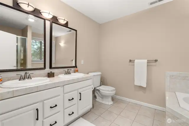 Primary bathroom with a luxurious soaking tub, a walk-in shower and dual sinks, offering functionality.
