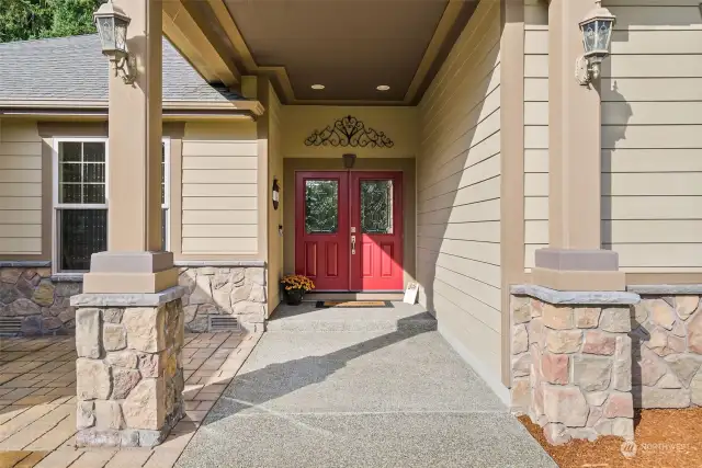 The inviting front-covered entry featuring double doors and stonework, makes a stunning first impression. The front patio overlooks a picturesque field.