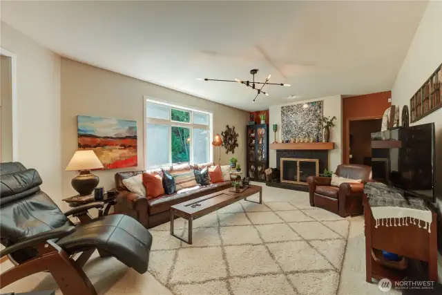Family room with views of the lush greenbelt. Double sided gas fireplace, and door to main floor rec room/bonus room.