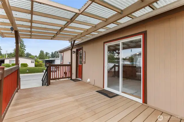 Covered side entrance of home with newer trex decking large sliding glass door and decorative wood railings
