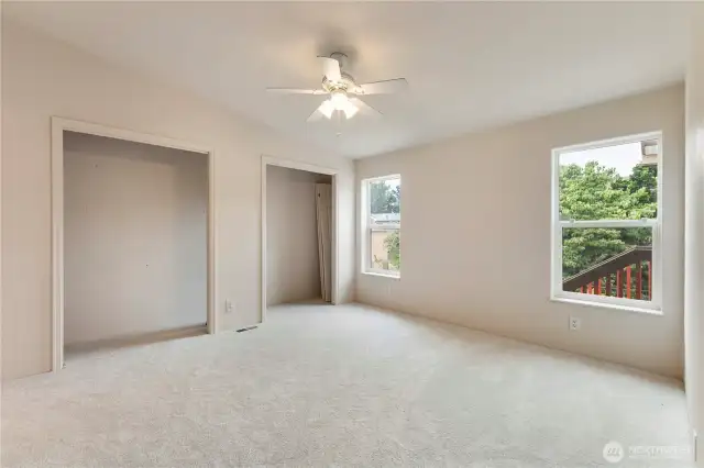 Second view of good sized primary bedroom with two large closets new carpeting and newer paint.  Closet doors are in closet.  There is high ceilings and ceilings fans also