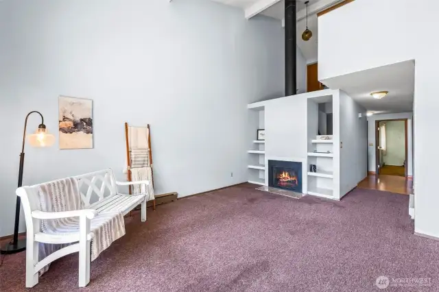Soaring ceilings, built in shelves and a comfy fireplace are great features of the living room/dining room combo.  Down the hallway is the entry to the Primary bedroom on the main level.  Yes, new flooring and paint will probably be one of the buyer's first investments, we know