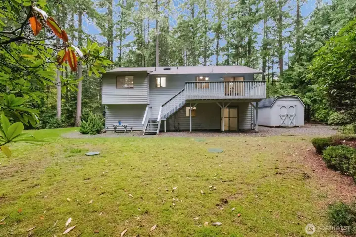 Large deck overlooking the backyard with a handy shed and open space for gatherings