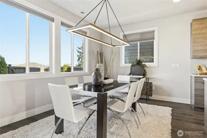 Well-appointed dining area featuring a designer light fixture, expansive windows overlooking the backyard and open space beyond, and a rare sense of privacy.