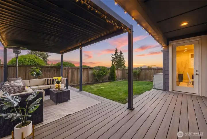As evening settles in, the covered pergola and composite deck transform into a warm and inviting outdoor retreat beneath the glow of twilight.