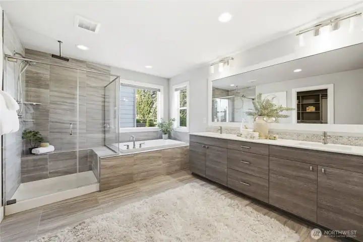 The primary suite showcases a spa-inspired 5-piece bath with soaking tub, tile shower, and large windows dressed with top-down/bottom-up shades for light and privacy control.