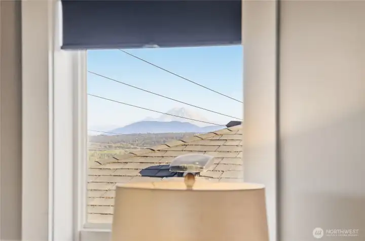 A glimpse of Mt. Rainier can be enjoyed from the primary suite window, a quiet reminder of the home’s elevated Pacific Northwest setting.