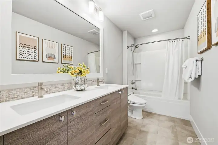 Hall bath with dual sinks and cohesive, sleek finishes consistent with the rest of the home.