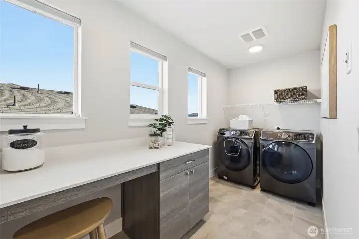 Bright upstairs laundry room includes cabinetry, folding counter, and abundant workspace.