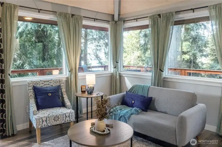 Cozy living room surrounded by windows & trees