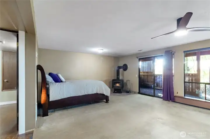 Additional angle of expansive lower-level living space with wood stove