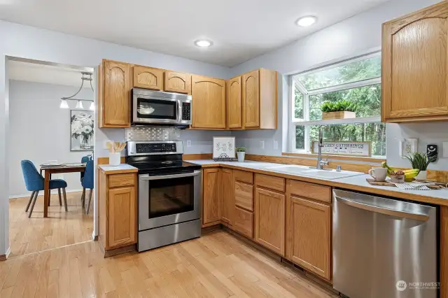 Nicely appointed kitchen with stainless steel appliances and view of backyard.