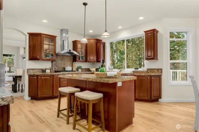 Open-concept kitchen with granite countertops, eating island, Stainless Steel appliances, gas range and high ceilings.