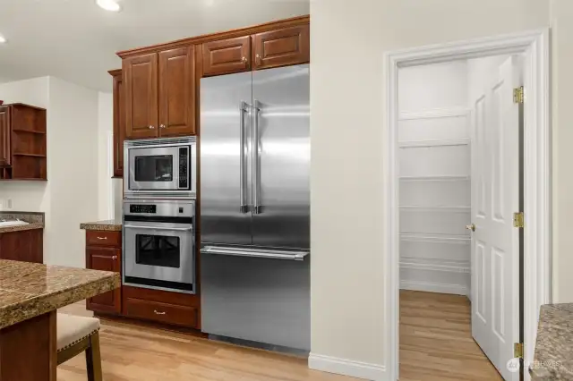 Open concept kitchen with stainless steel appliances and walk-in pantry.