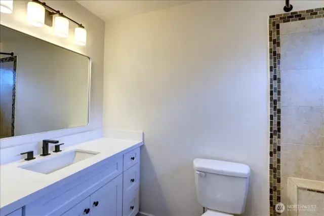 Primary full bath with new vanity, lights, mirror and flooring.