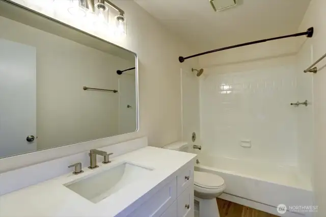 Main bath with new vanity, mirror, lights and flooring.
