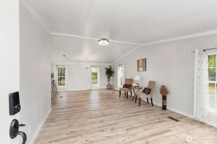 Bright and spacious open-concept living room with updated flooring, fresh paint, and large windows filling the home with natural light.