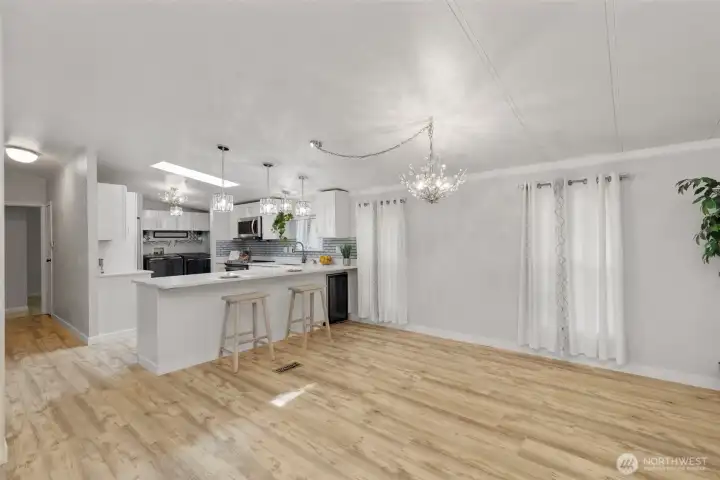 Stylish kitchen with quartz countertops, breakfast bar, pendant lighting, and stainless-steel appliances. Open to dining and living spaces