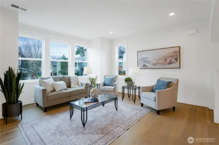 In the family room, tall ceilings and abundant natural light create an airy, welcoming centerpiece for daily living.  This great room is the hub of the home with the kitchen and dining area nearby.  The entire home has been freshly painted and the hardwood floors flow seamlessly throughout for a timeless look