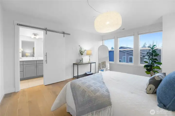 The entrance to the primary bath reveals a thoughtful layout, with a soaking tub to the right and a sleek shower to the left.  Beyond the shower lies the spacious walk-in closet, complete with an organizer system for effortless storage and style.