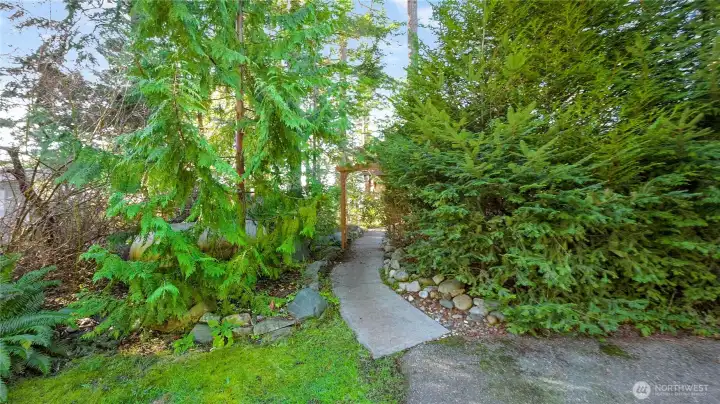 Entrance to 18404 Dr Joe Rd, A cedar arch and Pacific Northwest greenery greet you on your path to the home.  Welcome and enjoy!