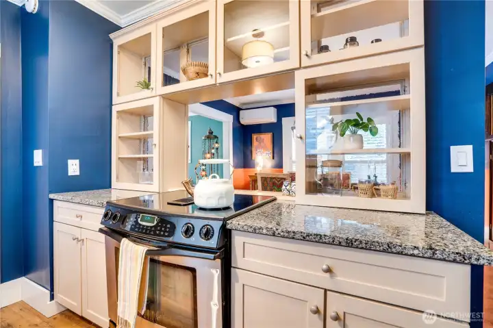 Glass-front cabinets create openness and connection between the kitchen and dining room. One of the home's mini splits units peaks through from the dining room for energy-efficient heating and cooling in every season.