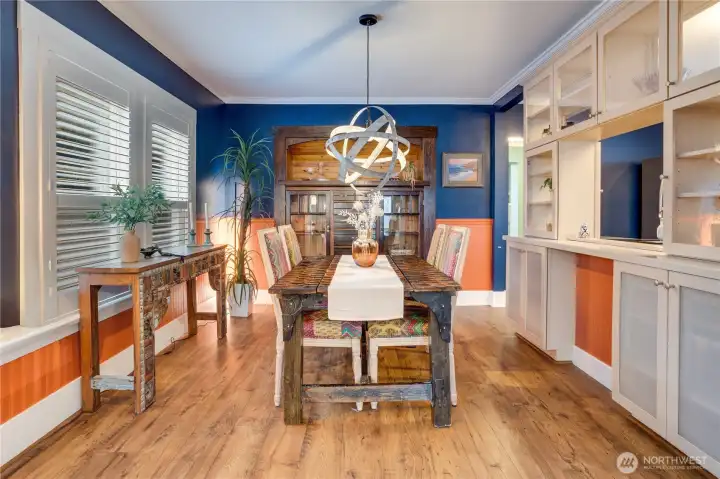 A cased opening leads from the living room into the dining room with its original hutch, and classic details like crown molding and wainscot. Notice how the cabinetry doesn't end in the kitchen, but extends to the dining room for additional cupboard storage.