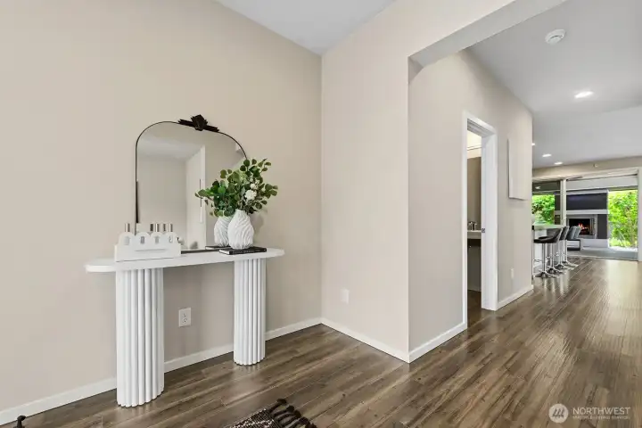 Walking into this lovely home, looking down the hall with the 1/2 bath on the left. and down to the 4 seat kitchen counter top seating, The kitchen is on the left of the seating. Living area and dining areas to the right. Straight ahead is the covered deck/patio with outdoor gas fireplace the back yard. To the right of this picture is the office/den to the right of the front door.