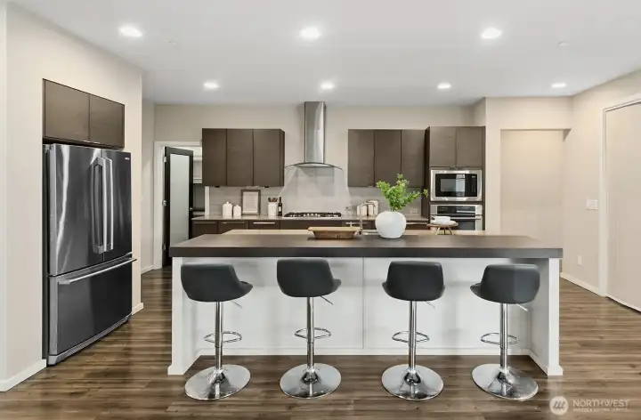 Full picture of the kitchen, 4 seat eating bar Refrigerator, door to the pantry. Full kitchen with built-in pull out shelving. Microwave, Built in oven and stove top.