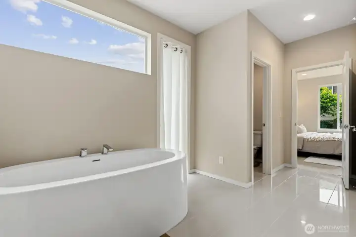 Looking at the main floor primary ensuite bath area, back into the bedroom. This bedroom is the southeast corner of the house. Looks into the peaceful relaxing backyard with all trees and flowering vegetation.