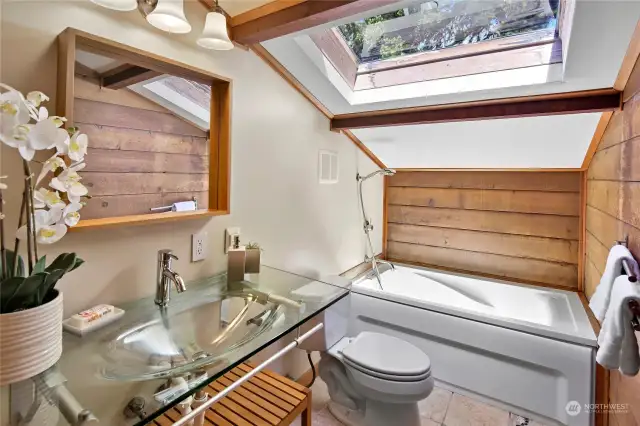 Upper-level full bathroom with skylight and modern glass-topped vanity