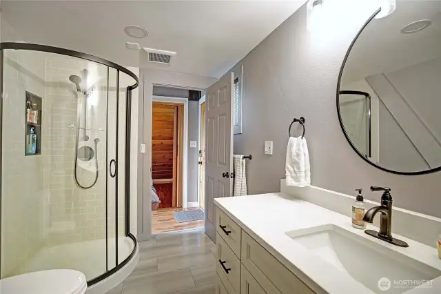 Updated bathroom with new flooring, vanity, lighting, hardware, and shower.