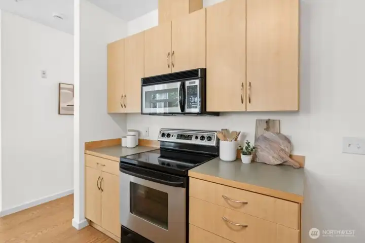 Kitchen with stainless steel oven/range and built-in microwave, plus a thoughtful integrated cutting board for convenient use of space.