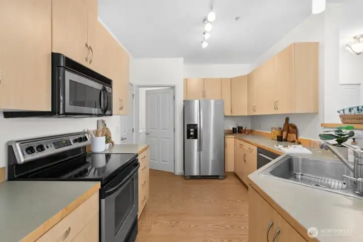 Well-appointed kitchen with abundant counter space, ample cabinetry, and a brand-new stainless steel refrigerator, with easy access to the adjacent pantry and separate laundry room conveniently located off the attached garage.