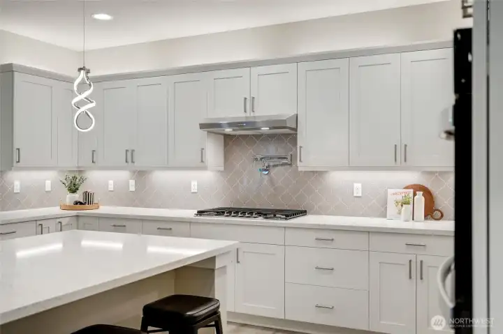 Pot filler and full-height designer tile backsplash add luxury and ease to the cooking zone.