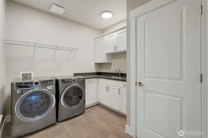 Well-designed laundry room with upgraded full-size appliances, ample storage, utility sink, and folding counter for easy everyday living.